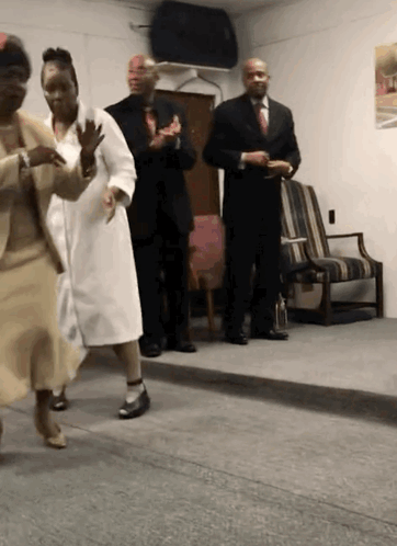 A Group Of People Are Dancing In A Room With A Man In A Suit GIF