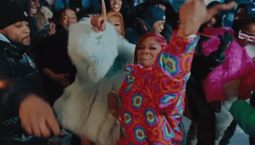 A Group Of People Are Dancing In A Room With A Woman Wearing A Colorful Jacket . GIF