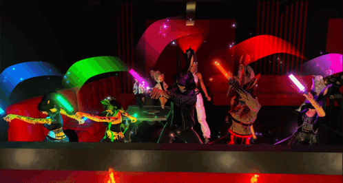A Group Of People Are Dancing In A Room With Glow In The Dark Sticks GIF
