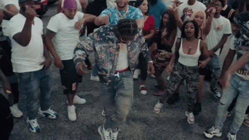 A Group Of People Are Dancing In A Street With A Man Wearing A Floral Jacket GIF