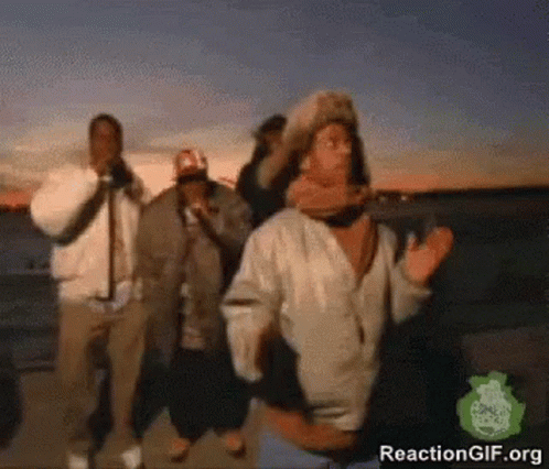 A Group Of People Are Dancing In Front Of A Body Of Water GIF
