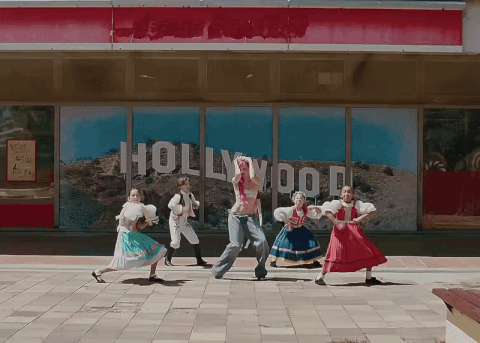 a group of people are dancing in front of a building that says hollywood
