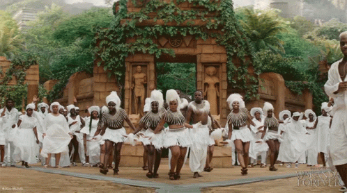 A Group Of People Are Dancing In Front Of A Building That Says Wanda Forever GIF