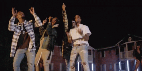 A Group Of People Are Dancing In Front Of A Building With The Letter S On The Front GIF