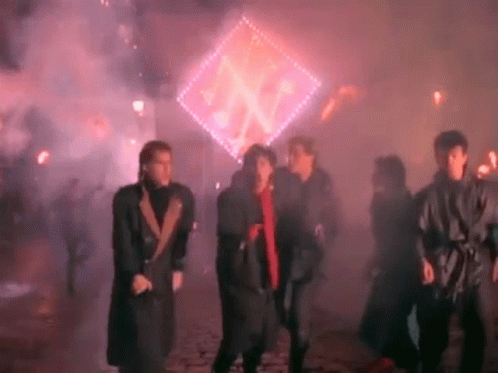 A Group Of People Are Dancing In Front Of A Glowing Sign . GIF