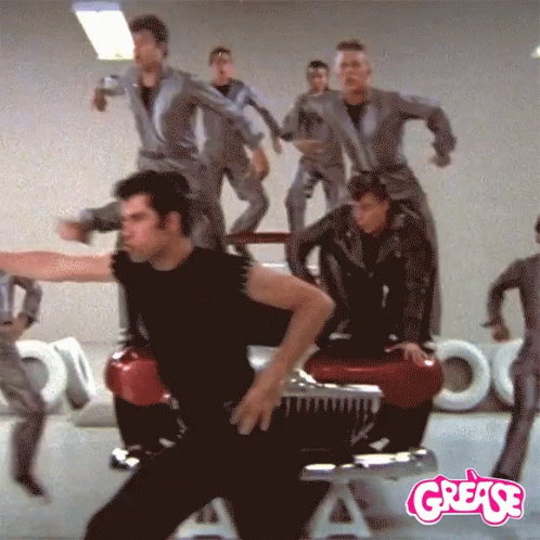 A Group Of People Are Dancing In Front Of A Grease Logo GIF