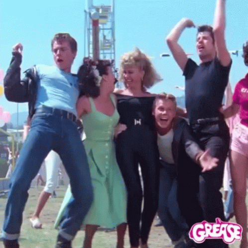 A Group Of People Are Dancing In Front Of A Grease Sign GIF