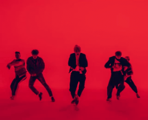 A Group Of People Are Dancing In Front Of A Red Background . GIF