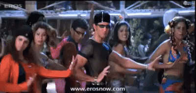 A Group Of People Are Dancing In Front Of A Screen Which Says Erosnow.com GIF