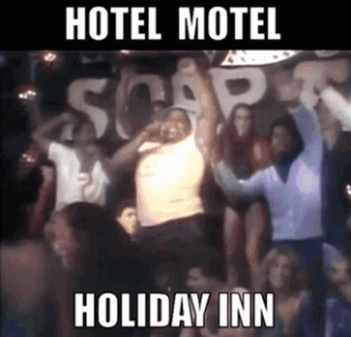 A Group Of People Are Dancing In Front Of A Sign That Says " Hotel Motel Holiday Inn " GIF