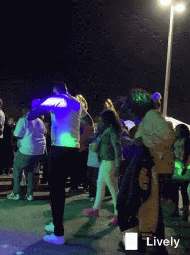 A Group Of People Are Dancing In Front Of A Sign That Says " Lively " GIF