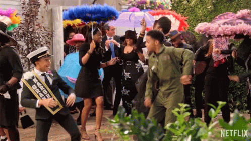A Group Of People Are Dancing In Front Of A Sign That Says Netflix On It GIF
