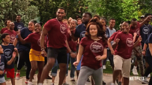 A Group Of People Are Dancing In Front Of A Sign That Says Netflix On It GIF