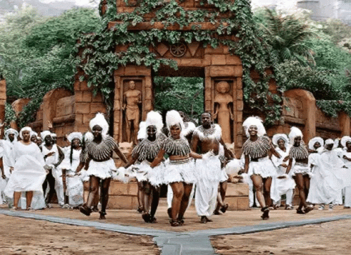 A Group Of People Are Dancing In Front Of A Statue . GIF