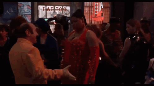 A Group Of People Are Dancing In Front Of A Tattoo Shop Sign GIF