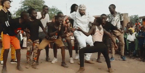 A Group Of People Are Dancing In The Dirt In Front Of A Crowd Of People . GIF