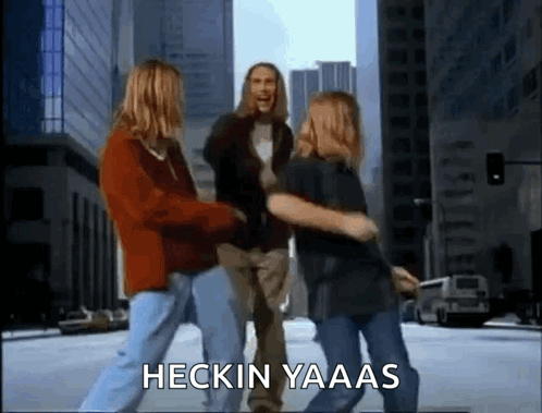 a group of people are dancing on a city street with the words heckin yaaas written on the bottom .