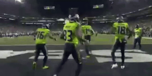 A Group Of People Are Dancing On A Football Field . GIF