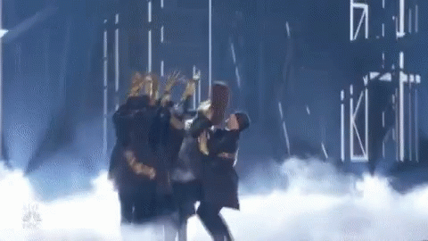 A Group Of People Are Dancing On A Stage In A Dark Room . GIF