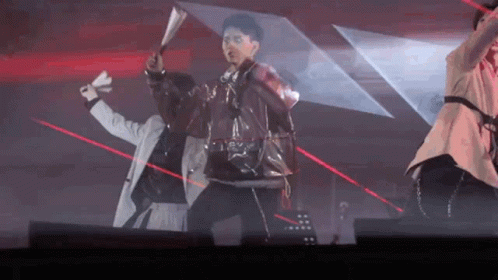 A Group Of People Are Dancing On A Stage With Red Lasers Behind Them . GIF