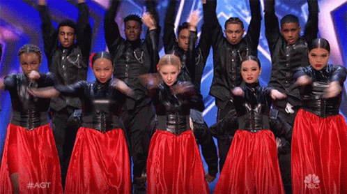 A Group Of People Are Dancing On A Stage With Their Arms In The Air GIF
