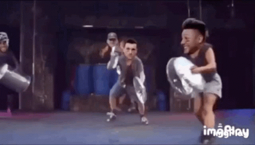 A Group Of People Are Dancing On A Stage With Their Faces On Their Heads . GIF