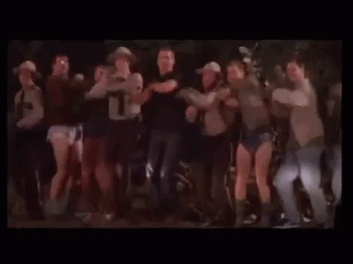 A Group Of People Are Dancing Together On A Stage In A Dark Room . GIF