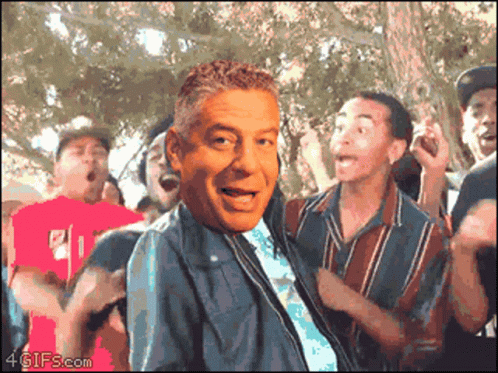 a group of people are dancing with a man 's face in the foreground and 4gifs.com in the bottom right corner