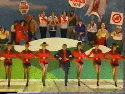A Group Of People Are Dancing With A Sign That Says Canada Now GIF