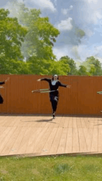 A Group Of People Are Dancing With Hula Hoops On A Wooden Deck . GIF