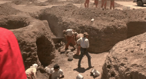 A Group Of People Are Digging In A Dirt Area GIF