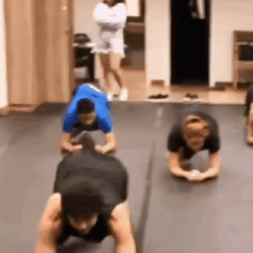 A Group Of People Are Doing Push Ups On The Floor . GIF