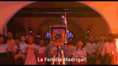 A Group Of People Are Gathered Around A Camera That Says La Familia Madrigal On It GIF
