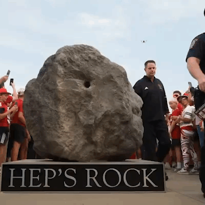 A Group Of People Are Gathered Around A Large Rock Called Hep 'S Rock GIF