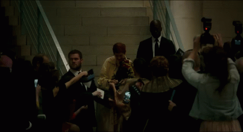 A Group Of People Are Gathered Around A Woman In A White Dress GIF