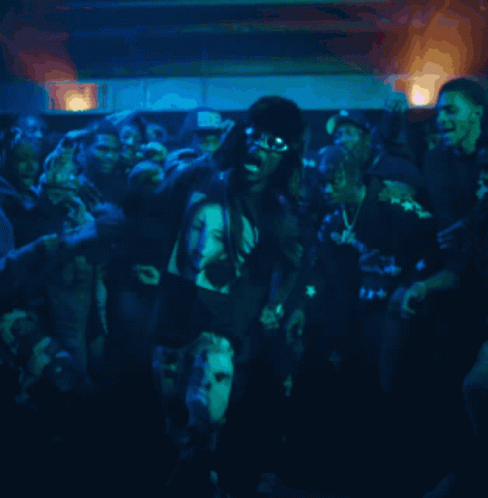A Group Of People Are Gathered In A Dark Room With A Man Wearing A Shirt That Says ' Bb ' GIF