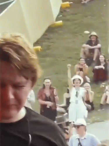 A Group Of People Are Gathered In A Field And One Woman Is Holding Her Fist Up In The Air GIF