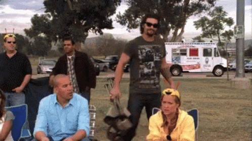 A Group Of People Are Gathered In A Park With An Ice Cream Truck Parked Behind Them GIF
