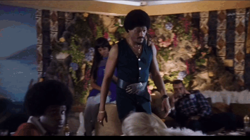 A Group Of People Are Gathered In A Room Including A Man In A Blue Outfit GIF