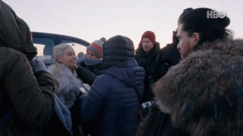 A Group Of People Are Gathered In Front Of A Car With Hbo On The Bottom Left GIF