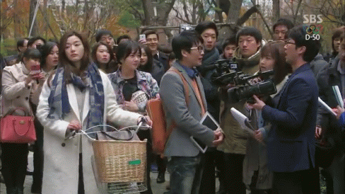A Group Of People Are Gathered In Front Of A Sbs Sign GIF