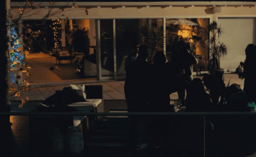 A Group Of People Are Gathered Outside A House At Night GIF