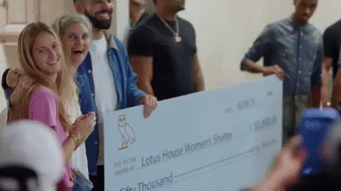 A Group Of People Are Holding A Large Check For Lotus House Women 'S Shelter . GIF