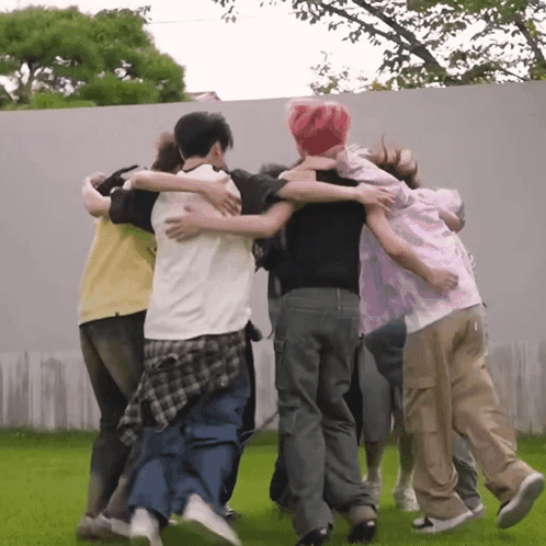 A Group Of People Are Hugging Each Other In A Huddle GIF