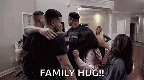 A Group Of People Are Hugging In A Living Room . GIF