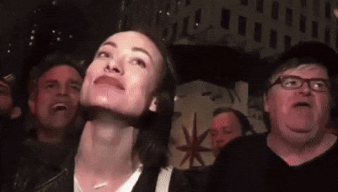 A Group Of People Are Looking Up At Something In A Dark Room GIF