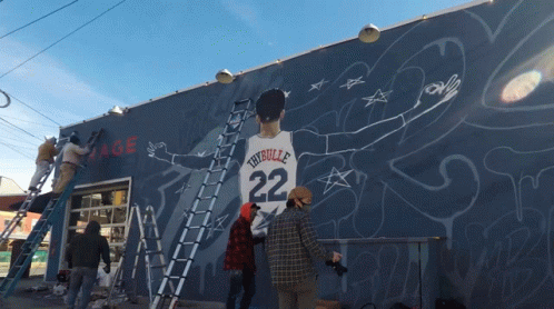 A Group Of People Are Painting A Mural Of A Man With The Number 22 On His Shirt GIF