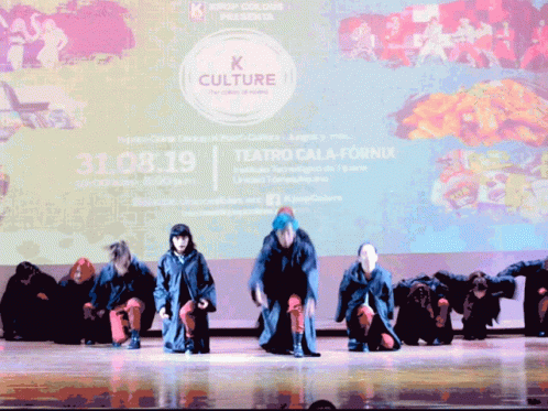 A Group Of People Are Performing On A Stage In Front Of A Large Screen That Says K Culture GIF