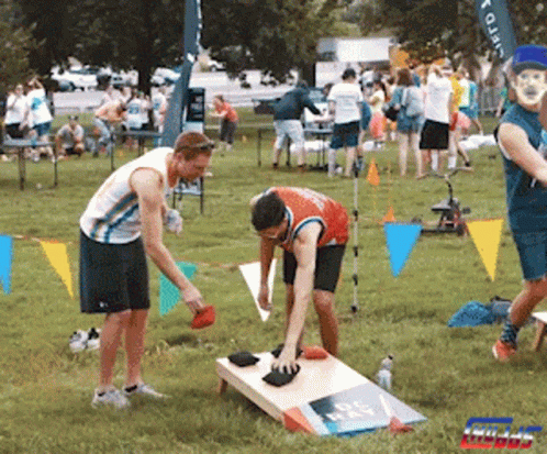 A Group Of People Are Playing A Game In A Park With A Sign That Says Giant GIF