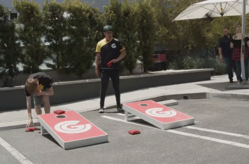 A Group Of People Are Playing A Game Of Cornhole GIF